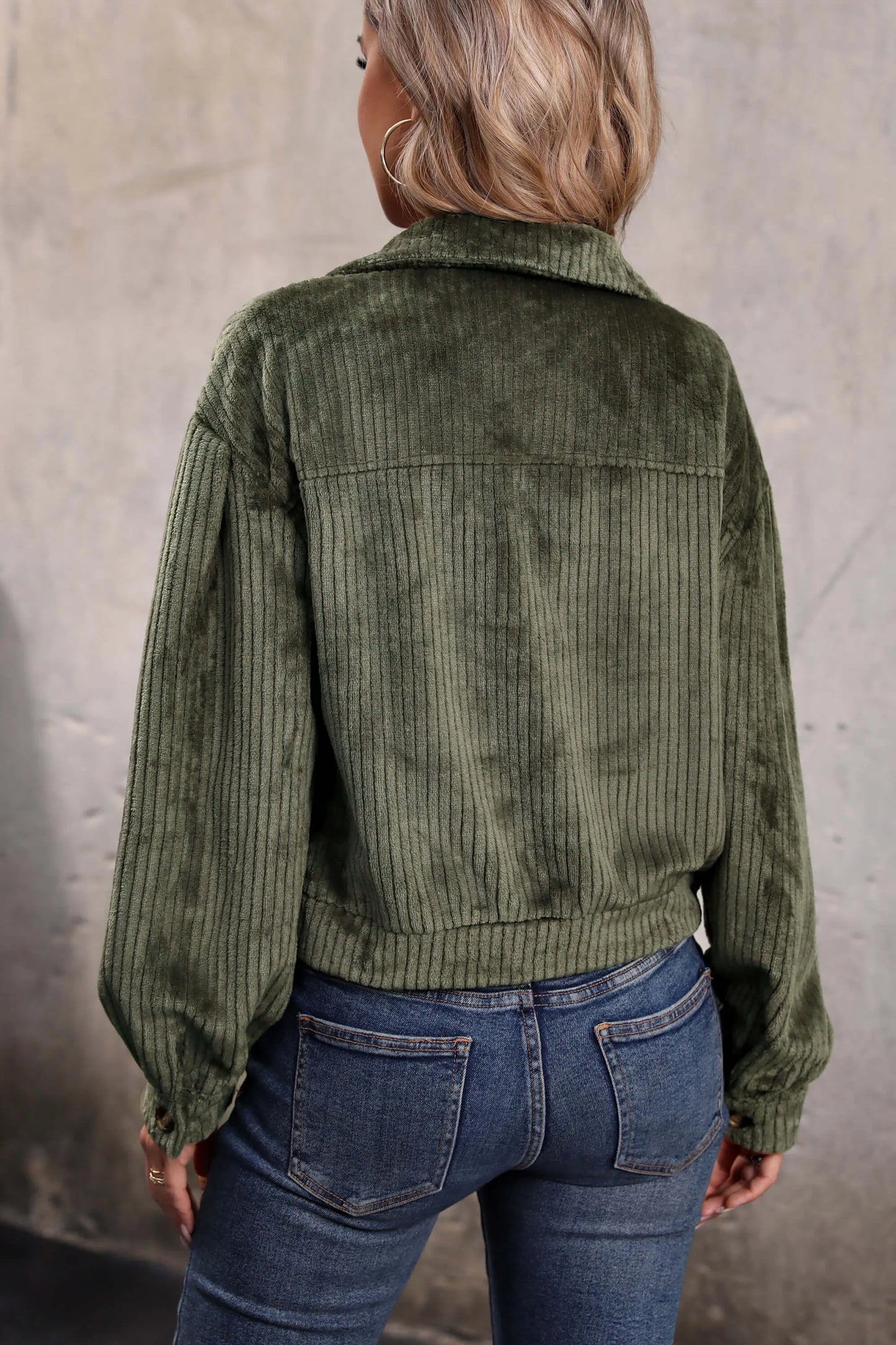 Olive - Woman wearing a green corduroy cropped jacket with button front and chest pockets, styled with a white crop top and jeans.