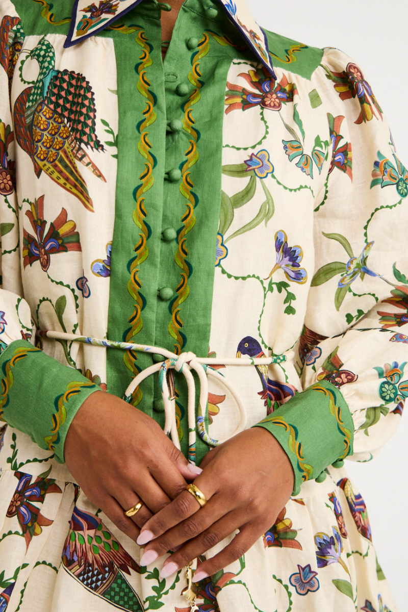 Green - Woman wearing a floral print long-sleeve mini dress with a collared neckline, covered buttons, and a tiered skirt against a plain background.