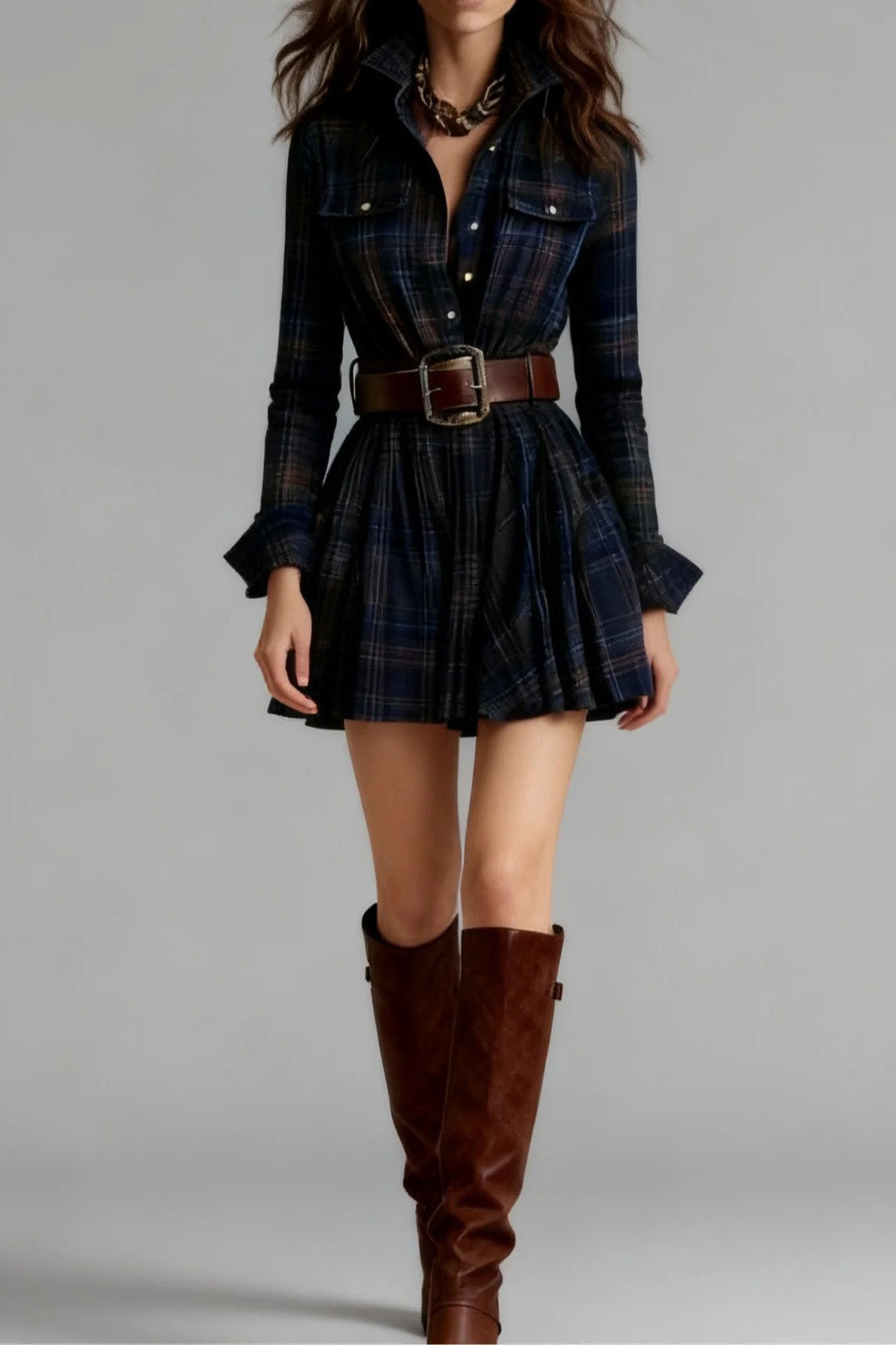 Blue - Model wearing a woven plaid long-sleeve mini shirtdress with a pleated skirt, styled with a wide statement belt and knee-high leather boots.