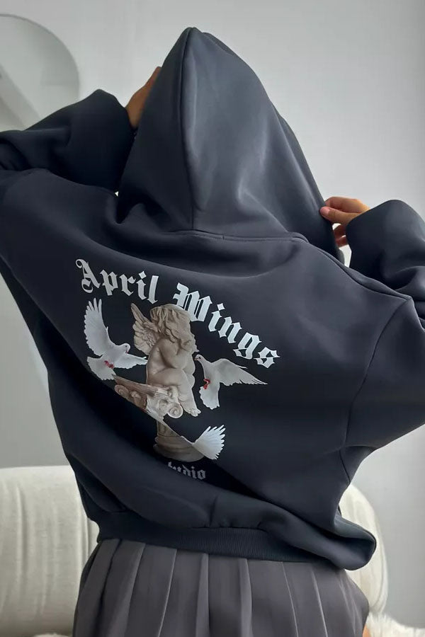Black - Back view of a woman wearing a dark grey oversized hoodie featuring a large graphic print of an angel statue and white doves, paired with a dark grey pleated mini skirt.
