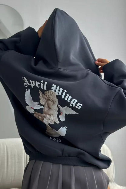 Black - Back view of a woman wearing a dark grey oversized hoodie featuring a large graphic print of an angel statue and white doves, paired with a dark grey pleated mini skirt.