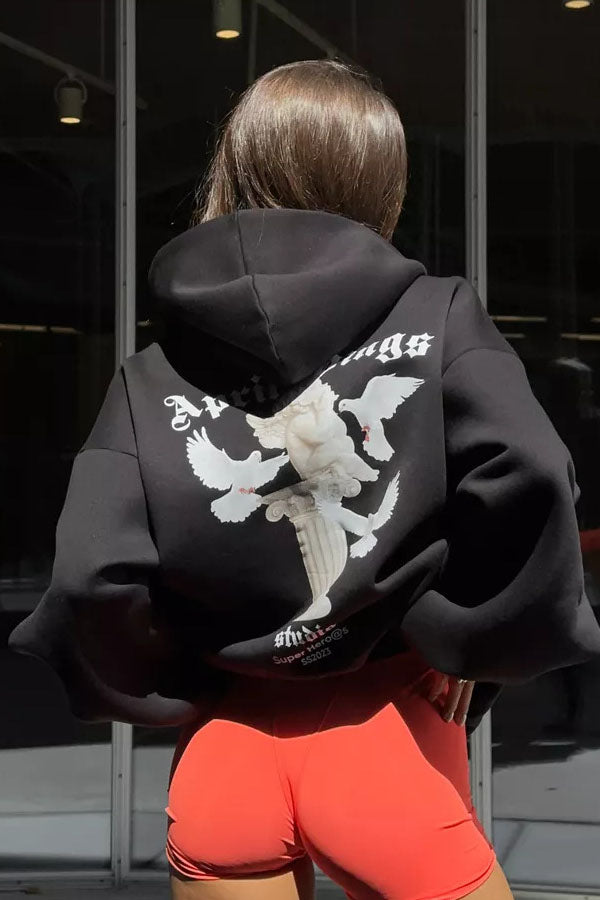 Black - Back view of a woman wearing a dark grey oversized hoodie featuring a large graphic print of an angel statue and white doves, paired with a dark grey pleated mini skirt.