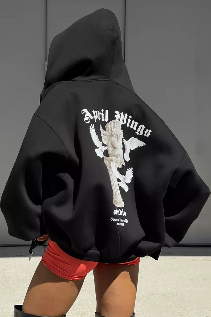 Black - Back view of a woman wearing a dark grey oversized hoodie featuring a large graphic print of an angel statue and white doves, paired with a dark grey pleated mini skirt.