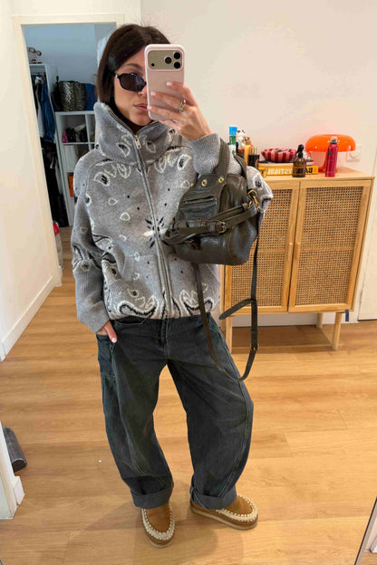 Grey - Woman taking a mirror selfie wearing a grey zip-up knit sweater with a black and white bandana pattern, featuring a high funnel neck and front pockets.