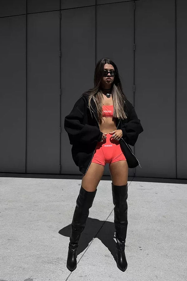 Black - Back view of a woman wearing a dark grey oversized hoodie featuring a large graphic print of an angel statue and white doves, paired with a dark grey pleated mini skirt.