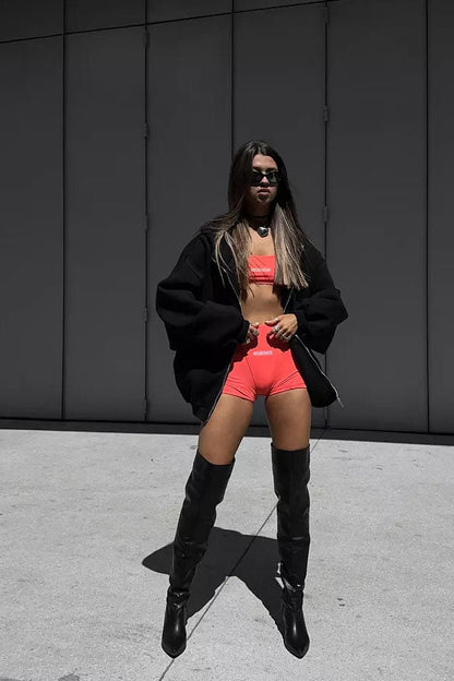 Black - Back view of a woman wearing a dark grey oversized hoodie featuring a large graphic print of an angel statue and white doves, paired with a dark grey pleated mini skirt.