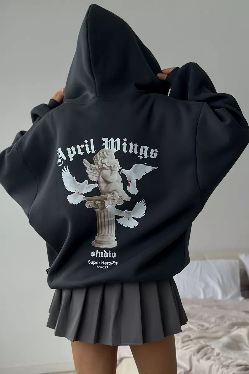 Black - Back view of a woman wearing a dark grey oversized hoodie featuring a large graphic print of an angel statue and white doves, paired with a dark grey pleated mini skirt.