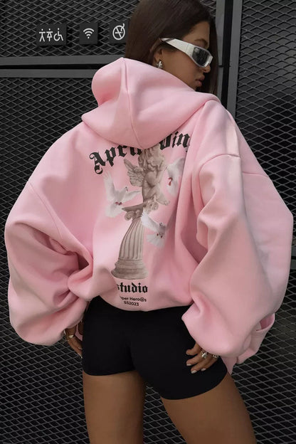 Pink - Back view of a woman wearing a dark grey oversized hoodie featuring a large graphic print of an angel statue and white doves, paired with a dark grey pleated mini skirt.