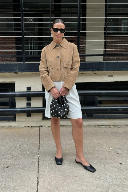 sand - Women's tan suede-look cropped jacket featuring a point collar, large button closures, and two front flap pockets, styled over white tailored shorts.