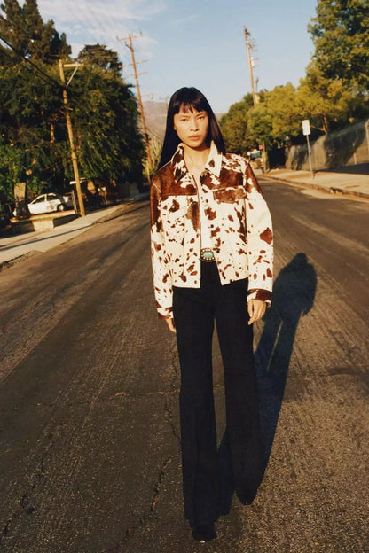 Dairy Cow - Women's cropped button-front jacket featuring a bold cow print pattern, pointed collar, and chest flap pockets.