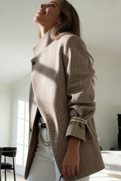 Plaid - A woman wearing a relaxed-fit, mid-length houndstooth jacket featuring an asymmetric high collar and distinctive ruched sleeves with tie details.