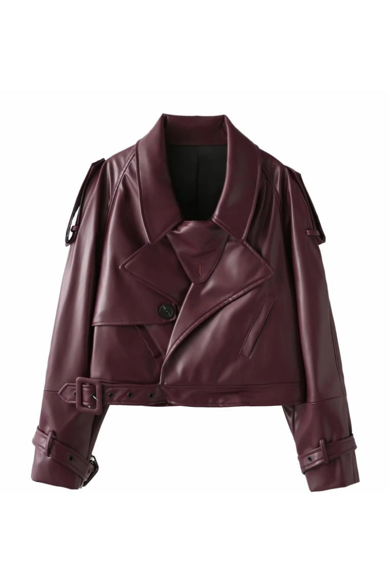 Red - Woman wearing an oversized burgundy faux leather moto jacket with exaggerated shoulders, wide collar, and belted cuffs, styled in a chic city setting.