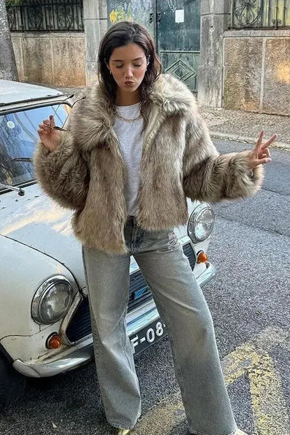 Brown - A woman sits on the hood of a vintage car wearing a fluffy, light brown faux fur cropped jacket with a large collar, styled with light wash wide-leg jeans.