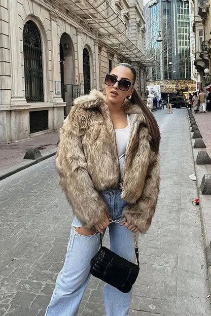 Brown - A woman sits on the hood of a vintage car wearing a fluffy, light brown faux fur cropped jacket with a large collar, styled with light wash wide-leg jeans.