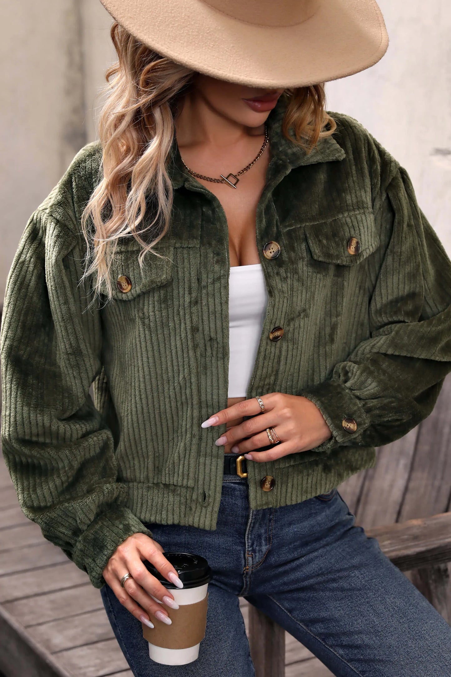 Olive - Woman wearing a green corduroy cropped jacket with button front and chest pockets, styled with a white crop top and jeans.