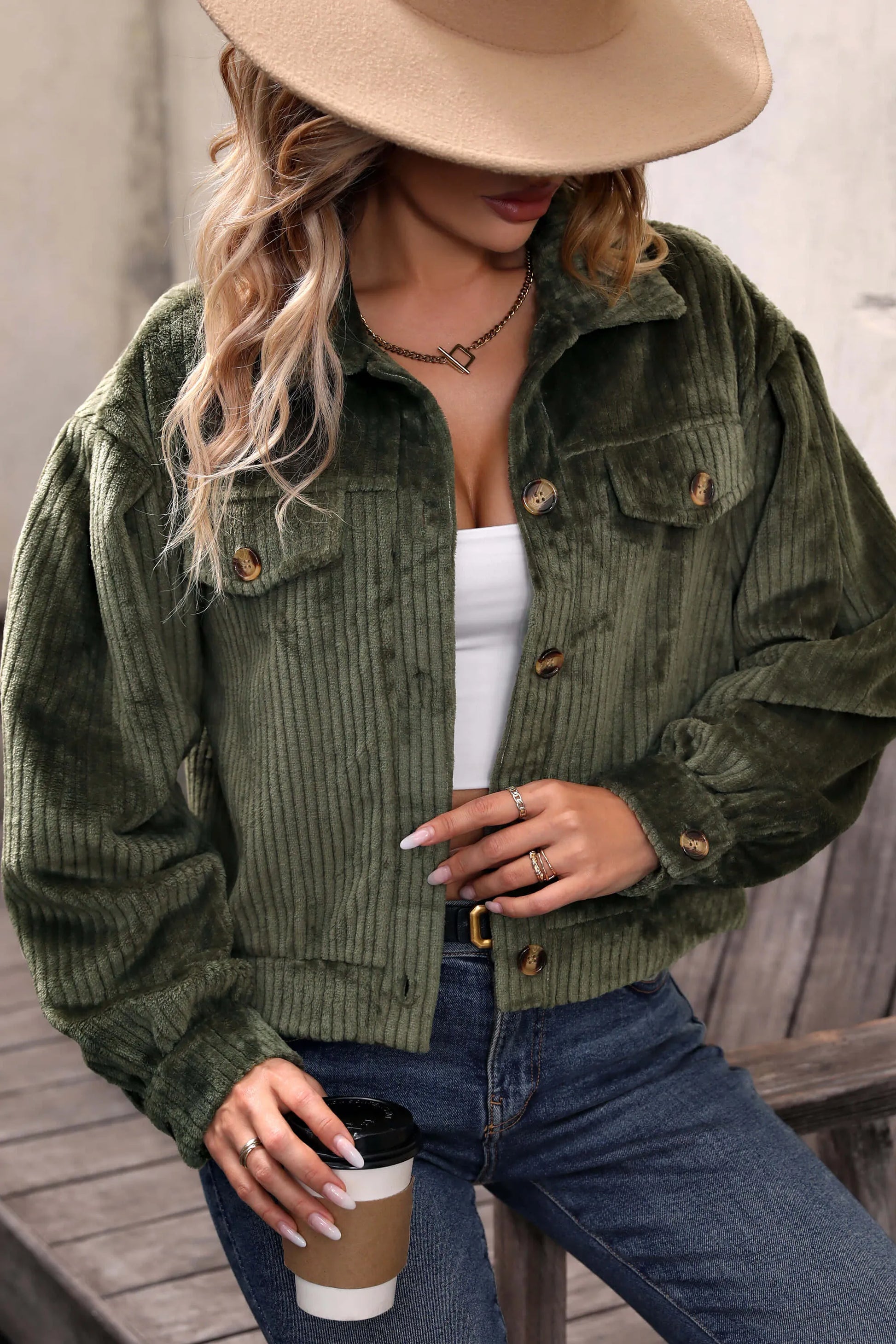 Olive - Woman wearing a green corduroy cropped jacket with button front and chest pockets, styled with a white crop top and jeans.