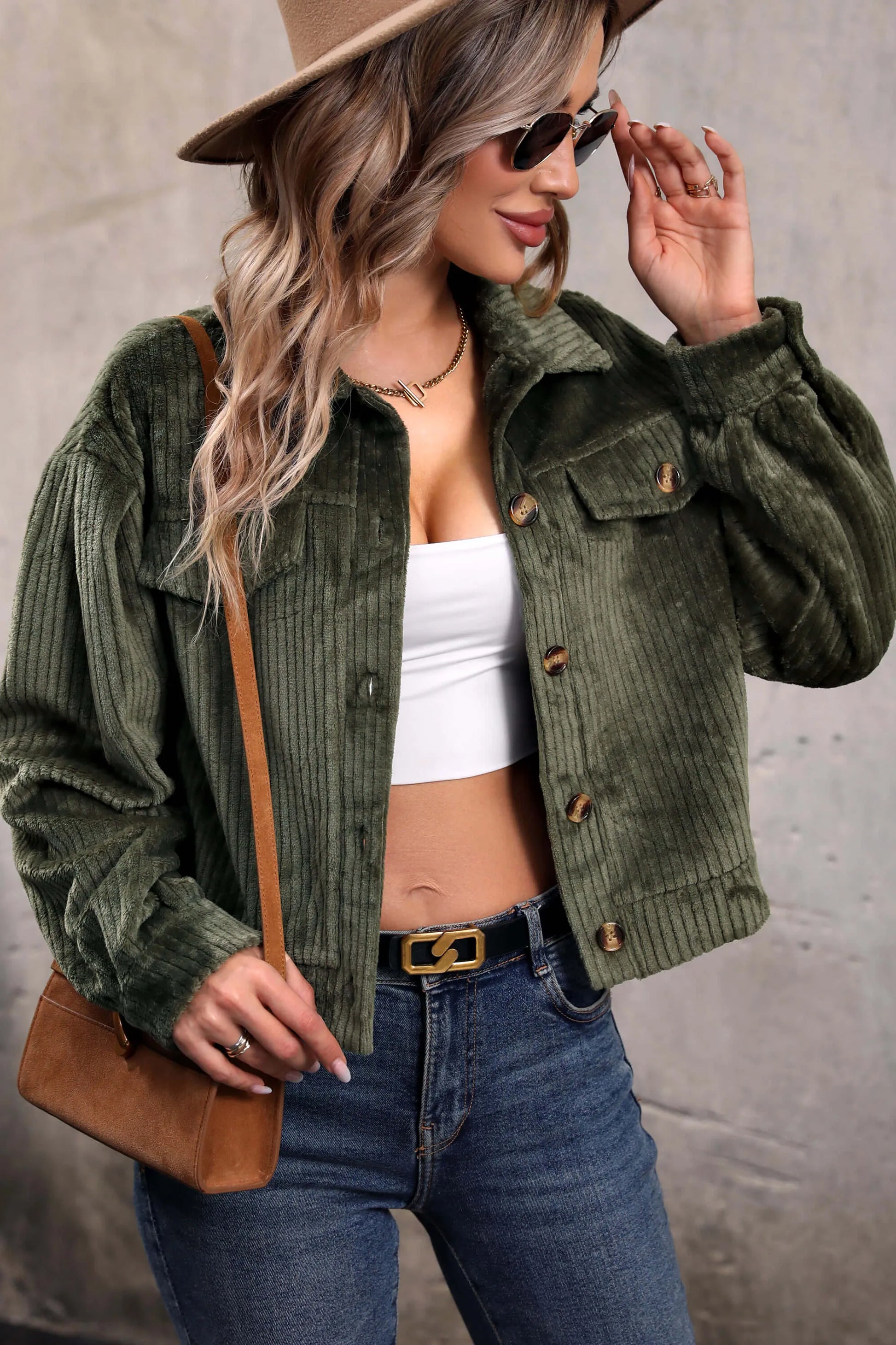 Olive - Woman wearing a green corduroy cropped jacket with button front and chest pockets, styled with a white crop top and jeans.
