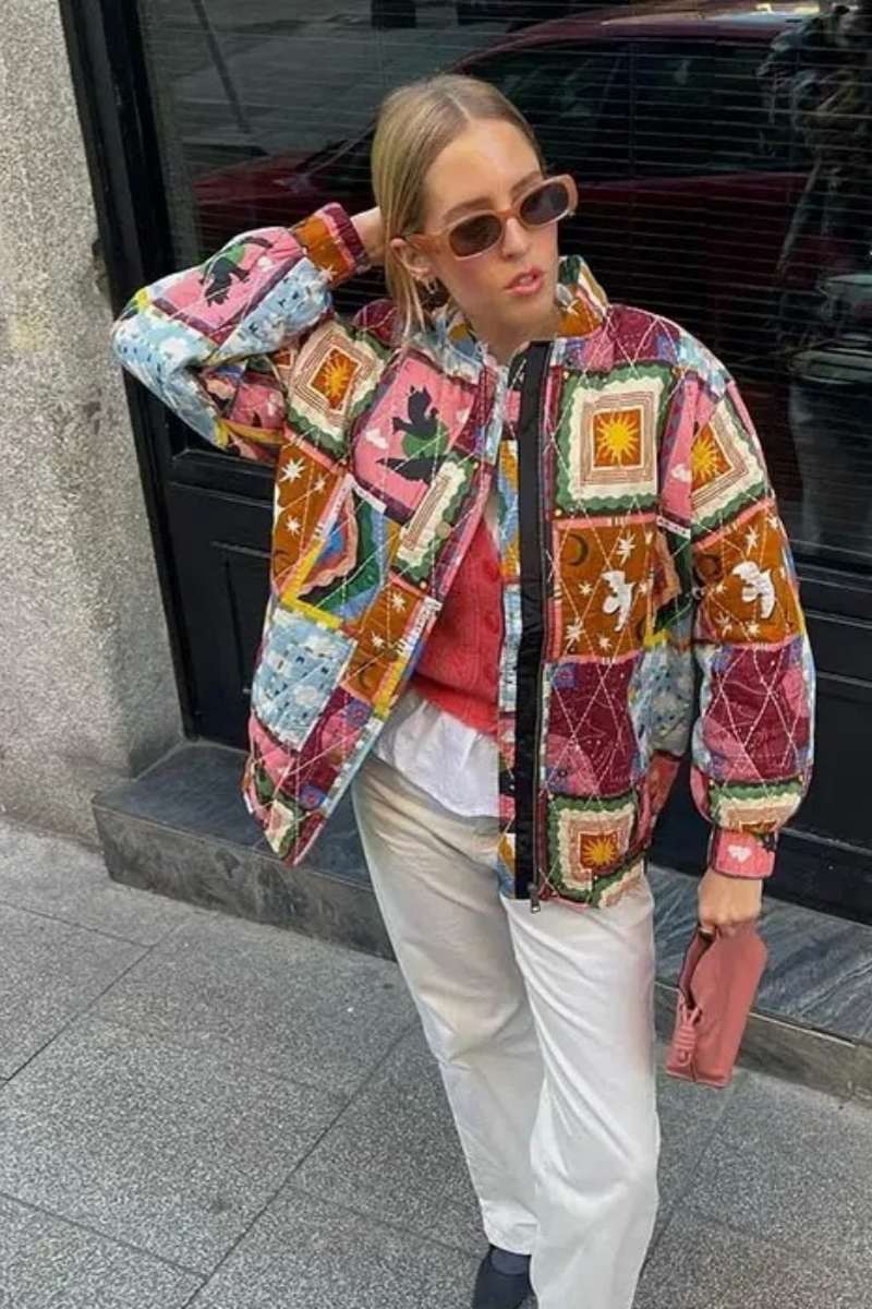 Multi - A woman wearing a vibrant, multi-coloured quilted patchwork jacket over a pink cardigan and white shirt, paired with white trousers.
