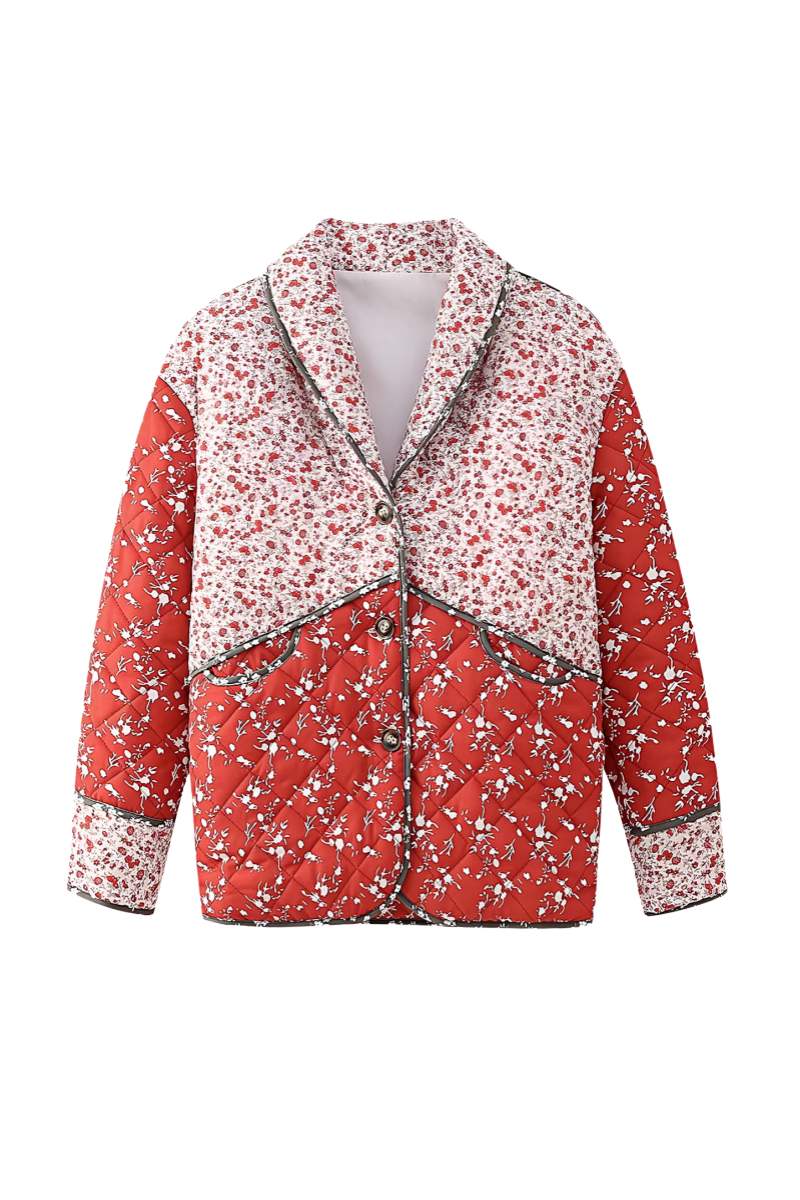 A woman wearing a hip-length quilted jacket featuring a mixed red and white floral print, contrast dark piping, and a button-front closure.
