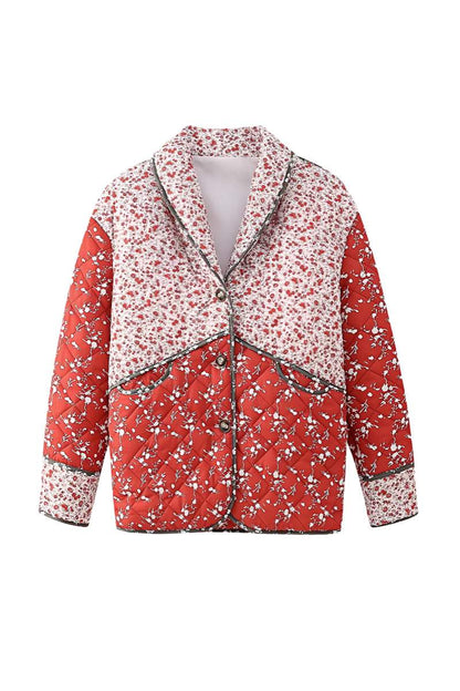 A woman wearing a hip-length quilted jacket featuring a mixed red and white floral print, contrast dark piping, and a button-front closure.