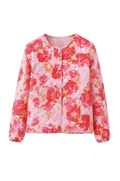 Red - Woman wearing a vibrant pink and red floral quilted bomber jacket with snap buttons, paired with light wash denim jeans and carrying a green fringed bag.