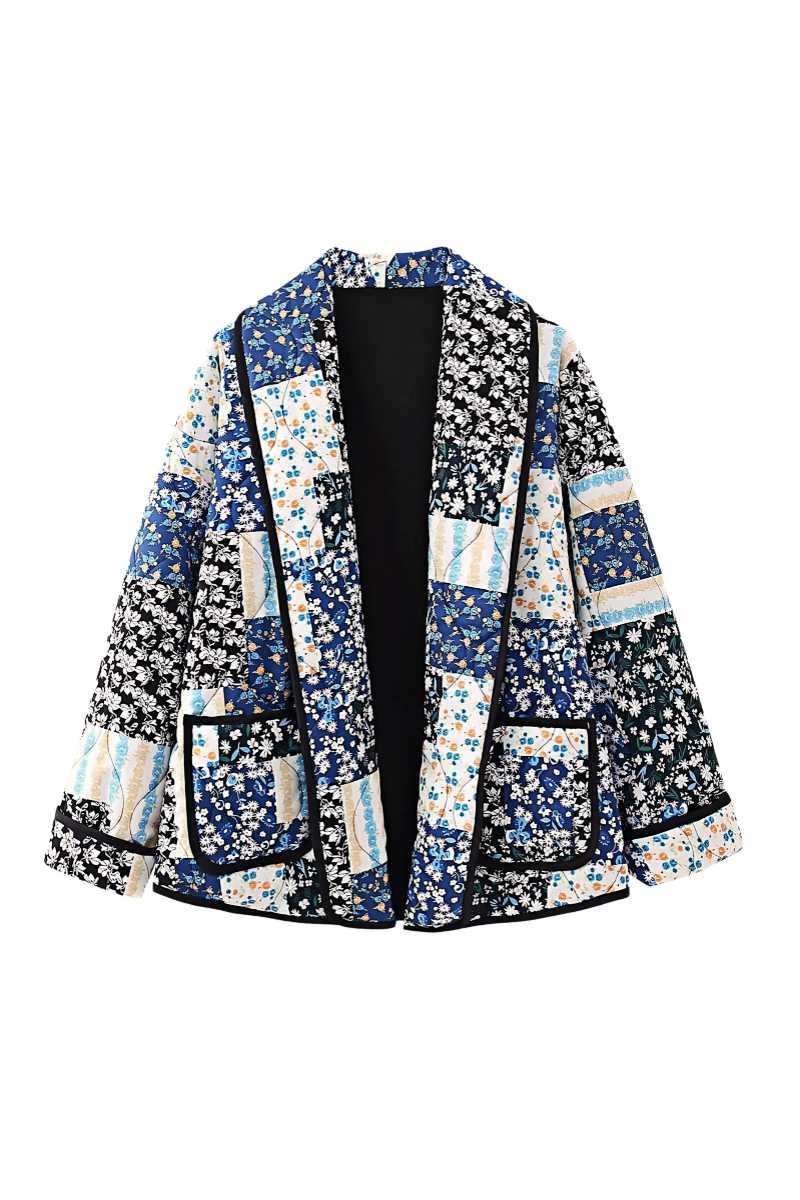 Woman wearing a quilted longline jacket featuring a blue and white floral patchwork design with contrasting dark binding.