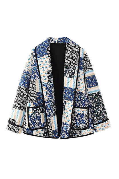 Woman wearing a quilted longline jacket featuring a blue and white floral patchwork design with contrasting dark binding.