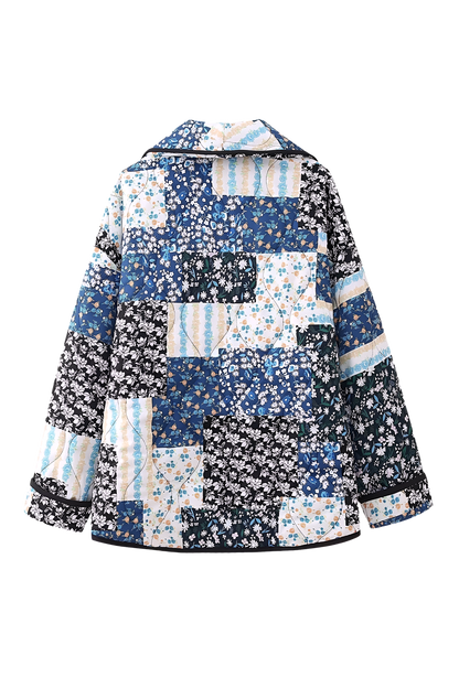 Woman wearing a quilted longline jacket featuring a blue and white floral patchwork design with contrasting dark binding.