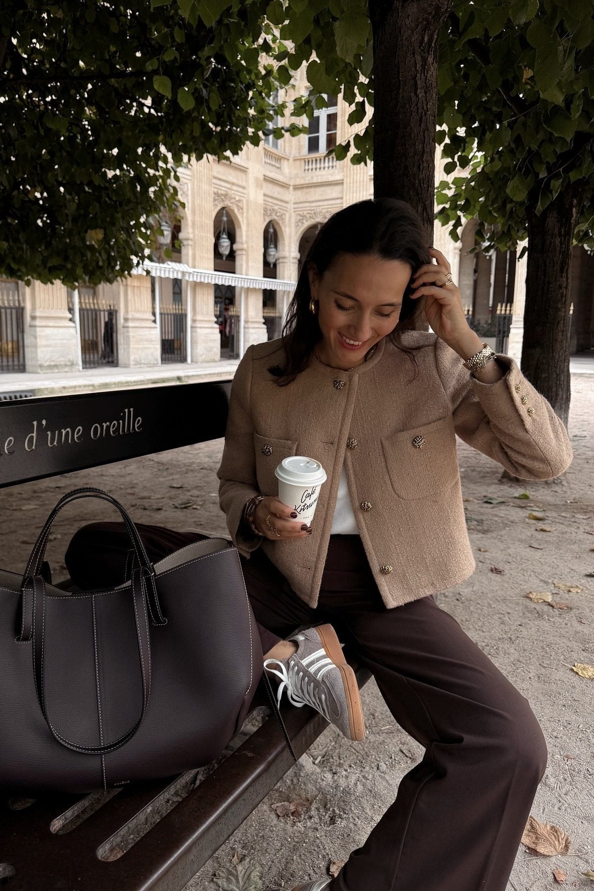 Women's smart casual textured cropped jacket in a neutral tone, featuring ornate buttons and a collarless design, styled over a white t-shirt and denim shorts.