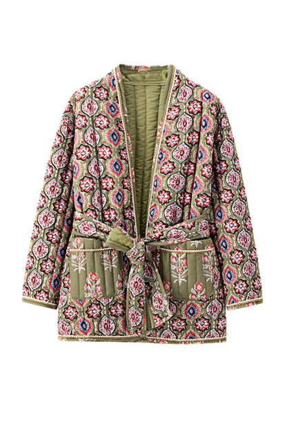 Multicolor - Woman in a cafe wearing an open-front quilted jacket with a colourful geometric medallion print over a black tank top and dark denim jeans.