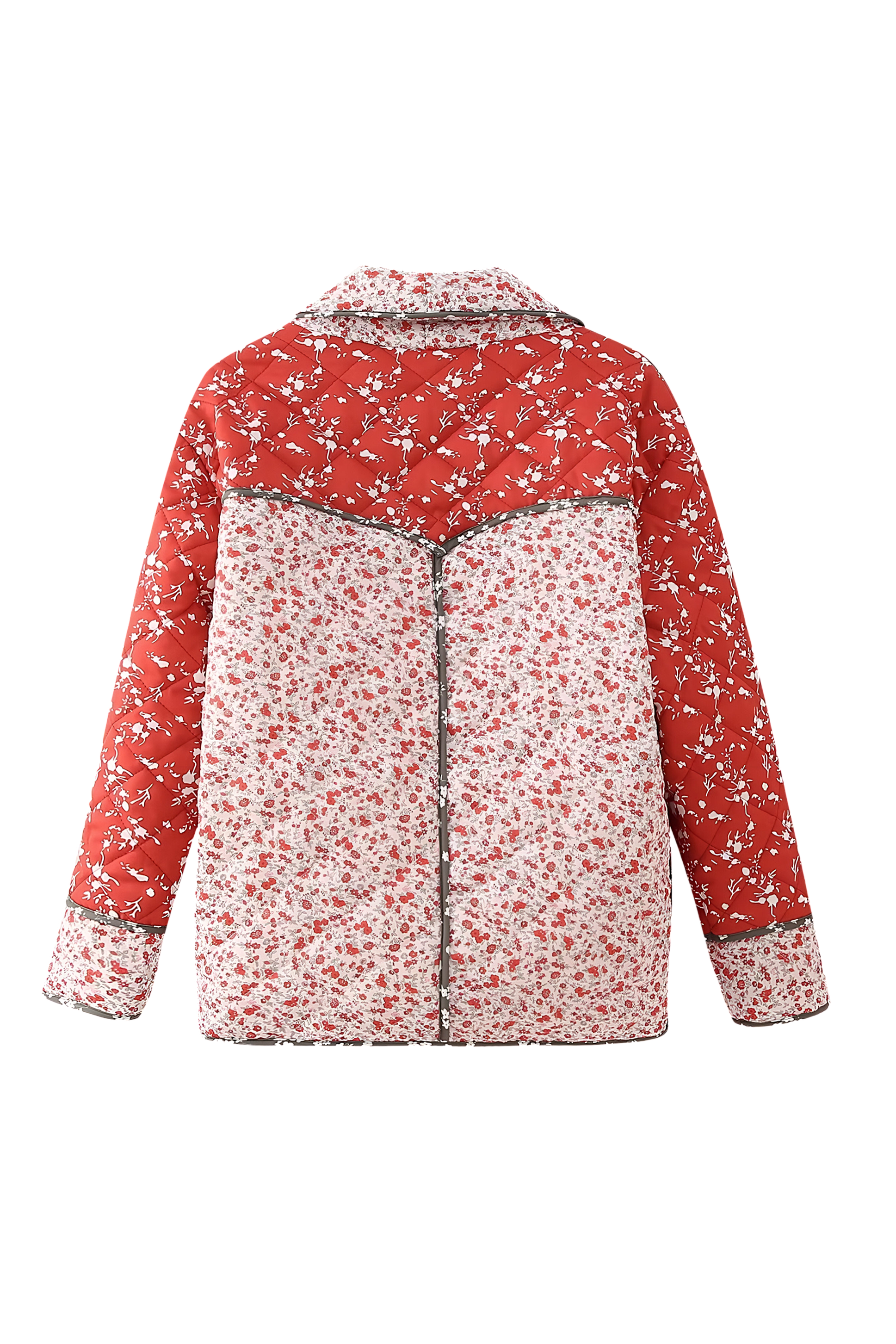 A woman wearing a hip-length quilted jacket featuring a mixed red and white floral print, contrast dark piping, and a button-front closure.