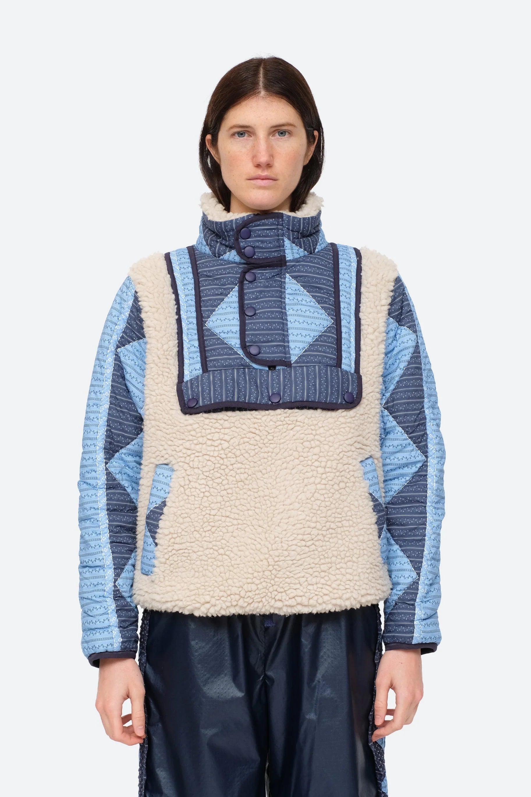 XL - Women's heavyweight pullover jacket featuring a cream fleece bodice, a high snap-button collar, and contrasting blue quilted sleeves with a geometric patchwork print.