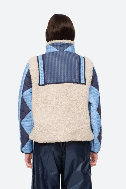 XL - Women's heavyweight pullover jacket featuring a cream fleece bodice, a high snap-button collar, and contrasting blue quilted sleeves with a geometric patchwork print.