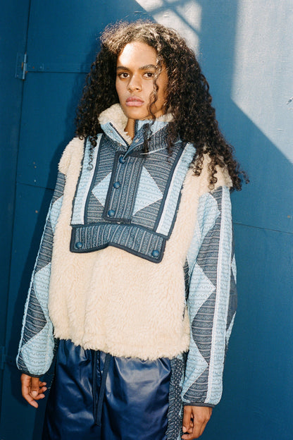 XL - Women's heavyweight pullover jacket featuring a cream fleece bodice, a high snap-button collar, and contrasting blue quilted sleeves with a geometric patchwork print.