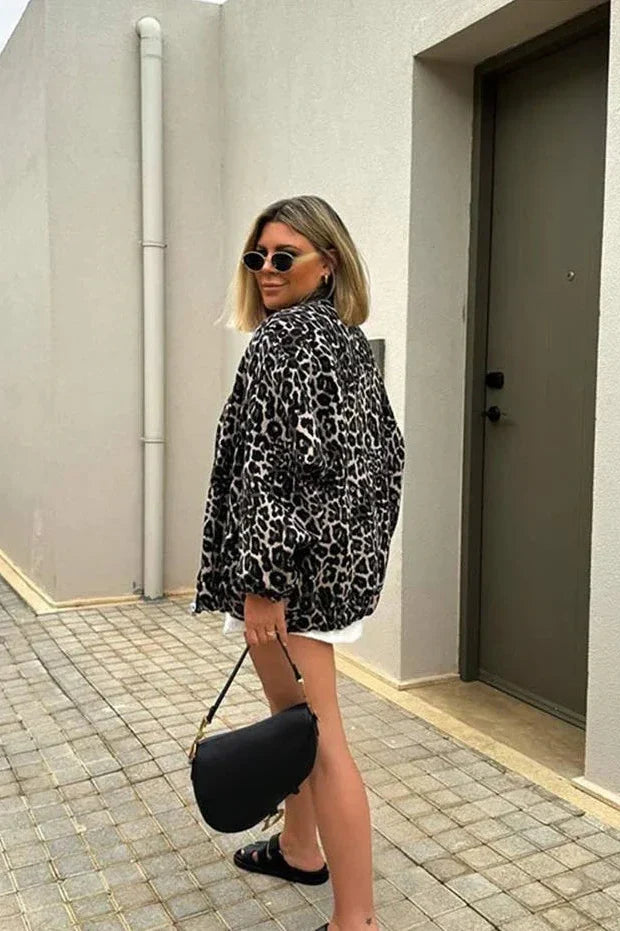 Leopard Print - A woman wearing an oversized bomber jacket with a leopard print, styled over a black crop top and beige ribbed mini skirt.