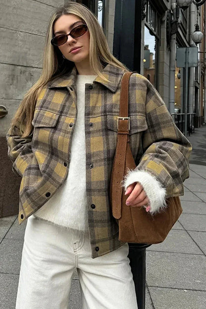 Plaid - Woman wearing an oversized yellow and brown plaid shirt jacket over a white fluffy sweater and white jeans, walking down a city street.