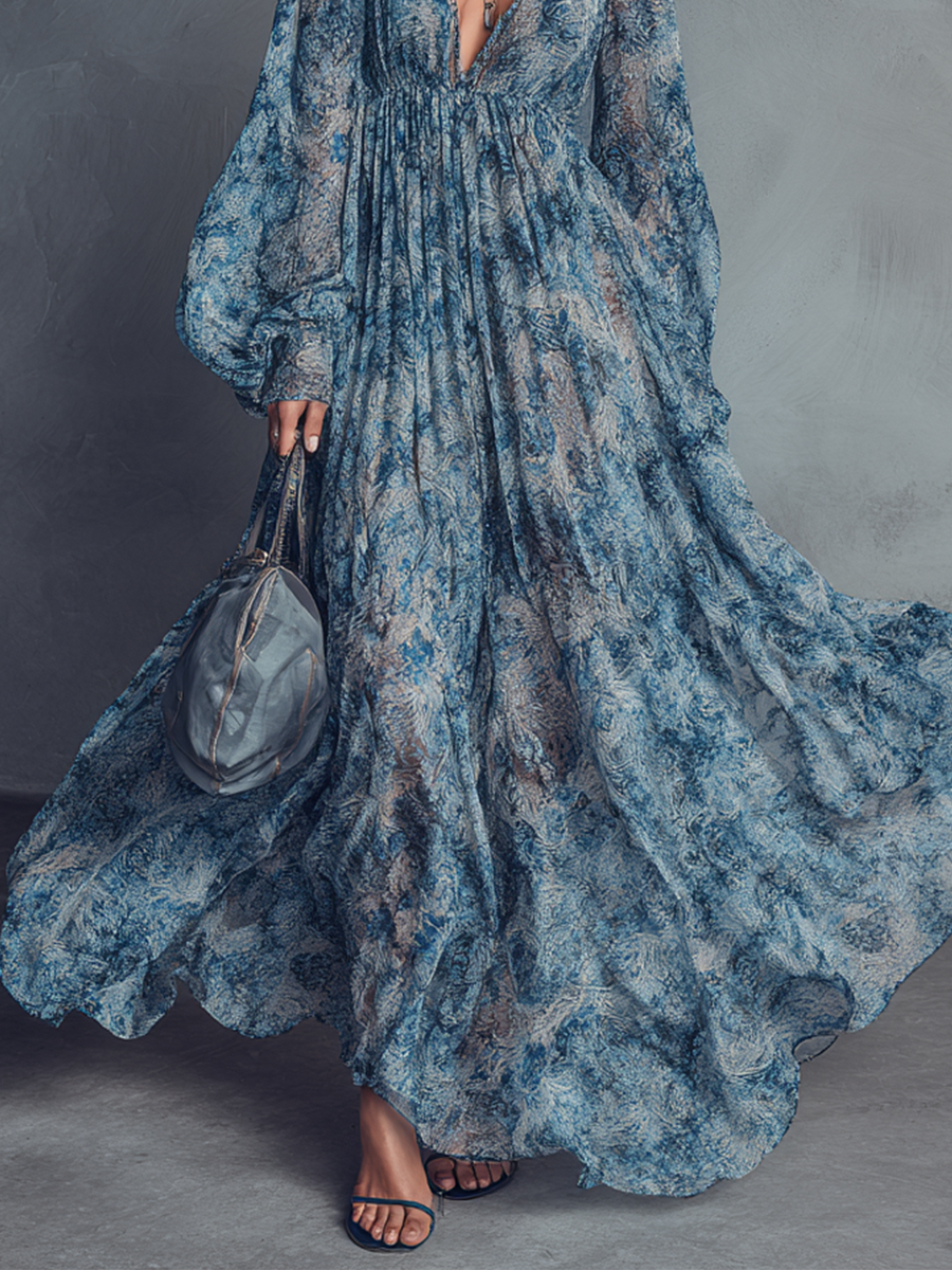 Blue - A model wearing a floor-length, long-sleeved maxi dress in a blue and grey abstract print chiffon, featuring a deep plunging V-neckline and voluminous balloon sleeves.