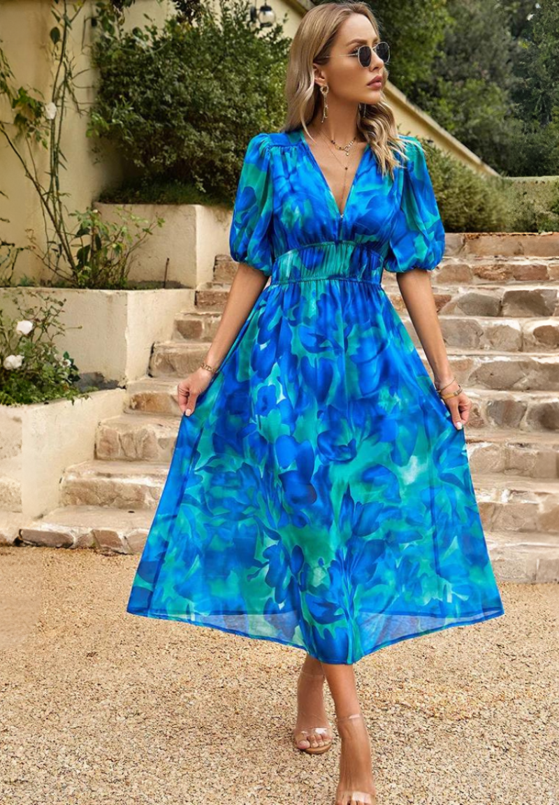 Floral - Women's flowing midi dress featuring a V-neckline, half puff sleeves, and a large-scale abstract floral print in muted earthy tones, styled with a woven clutch.