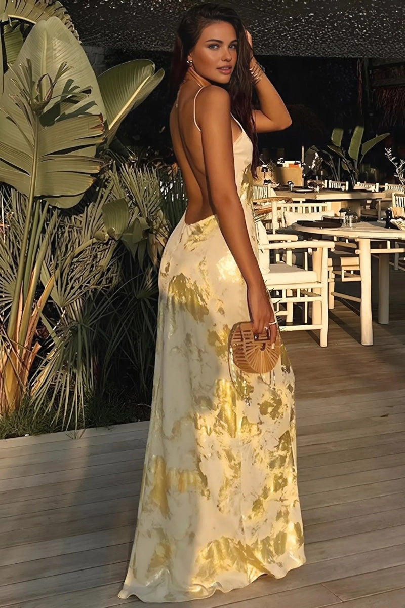 A woman wearing a sleeveless, floor-length satin slip dress with a gold and cream abstract print, featuring a V-neckline and thin straps.