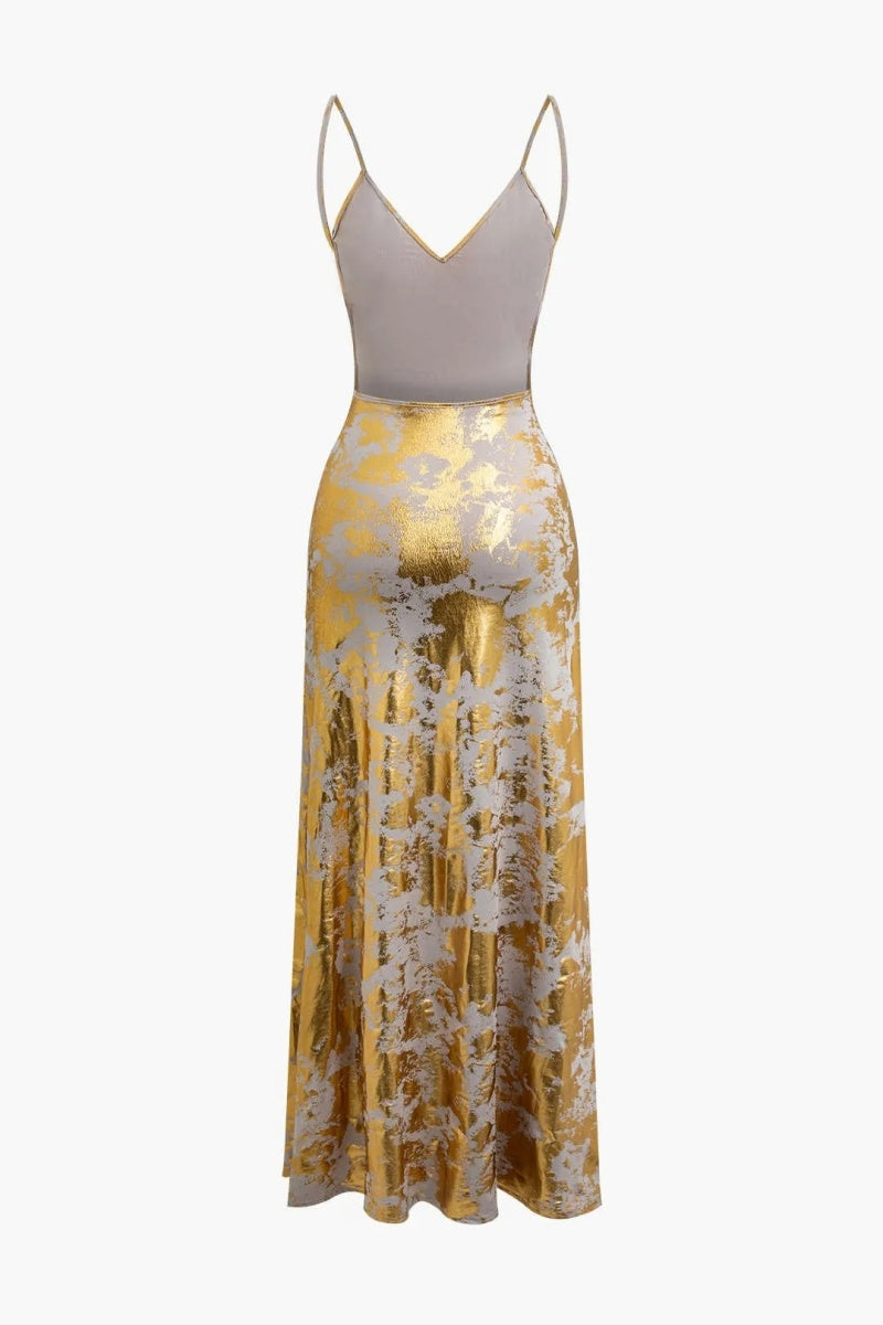 Gold - A woman wearing a sleeveless, floor-length satin slip dress with a gold and cream abstract print, featuring a V-neckline and thin straps.