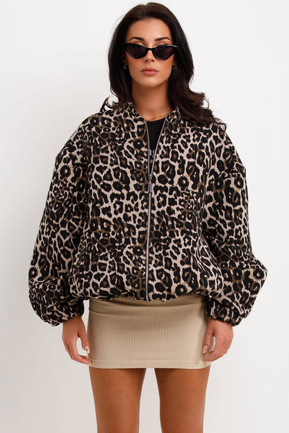 Leopard Print - A woman wearing an oversized bomber jacket with a leopard print, styled over a black crop top and beige ribbed mini skirt.