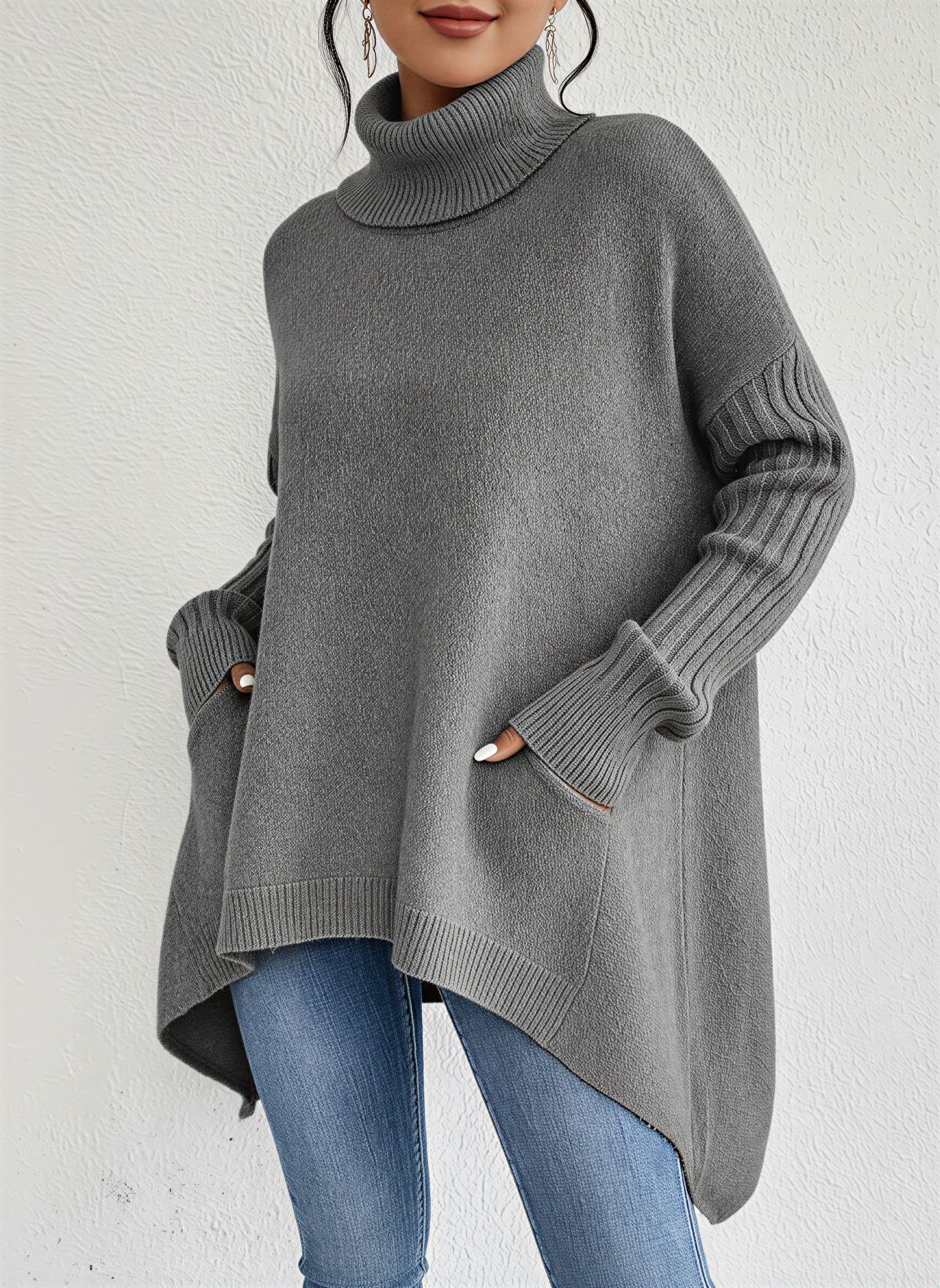 Gray - A woman wearing a blue oversized knit turtleneck sweater with ribbed sleeves and an asymmetrical high-low hem, paired with blue jeans.