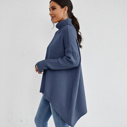 Brown - A woman wearing a blue oversized knit turtleneck sweater with ribbed sleeves and an asymmetrical high-low hem, paired with blue jeans.