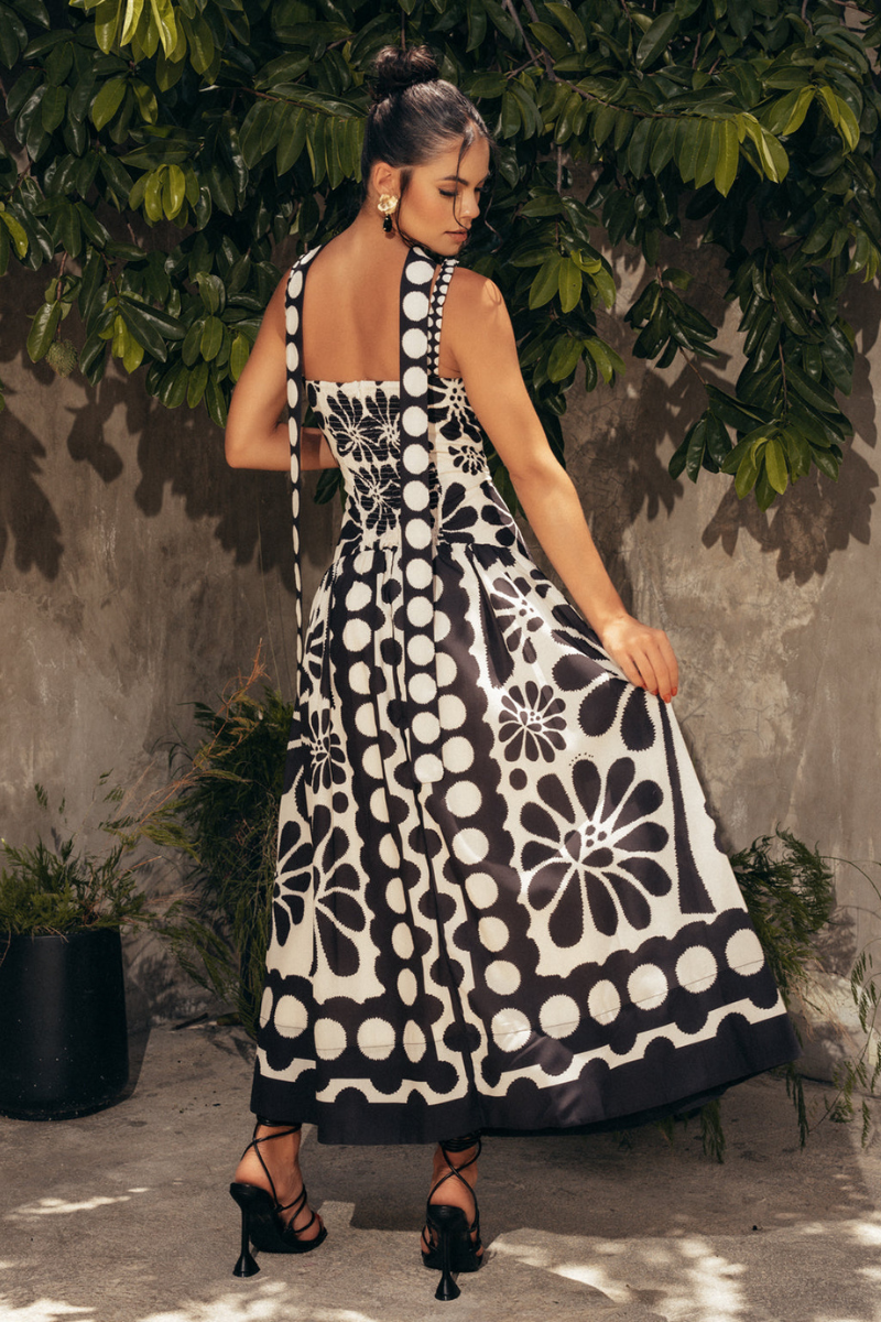 Black - A woman wearing a black and white maxi dress with a bold, oversized floral print, featuring a square neckline, wide straps, and a gathered drop waist.