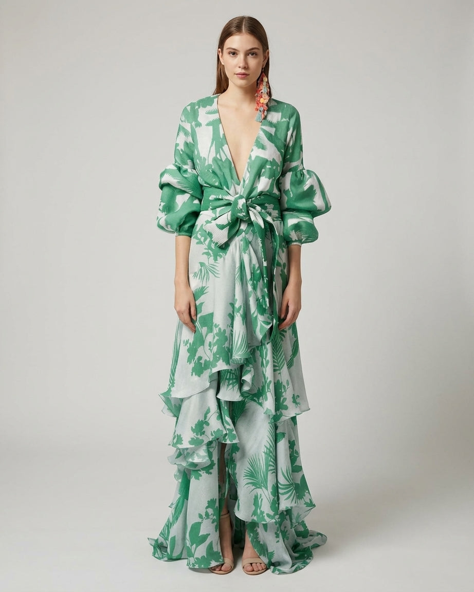 Light Green - A woman wearing a pale blue and mustard yellow botanical print maxi dress featuring a deep V-neckline, voluminous balloon sleeves, a belted waist, and a cascading tiered ruffle skirt.