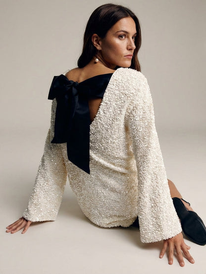 White - Model wearing a cream-coloured, highly textured bouclé knit mini dress with a high neckline, long sleeves, and an A-line silhouette, paired with black pointed-toe heels.
