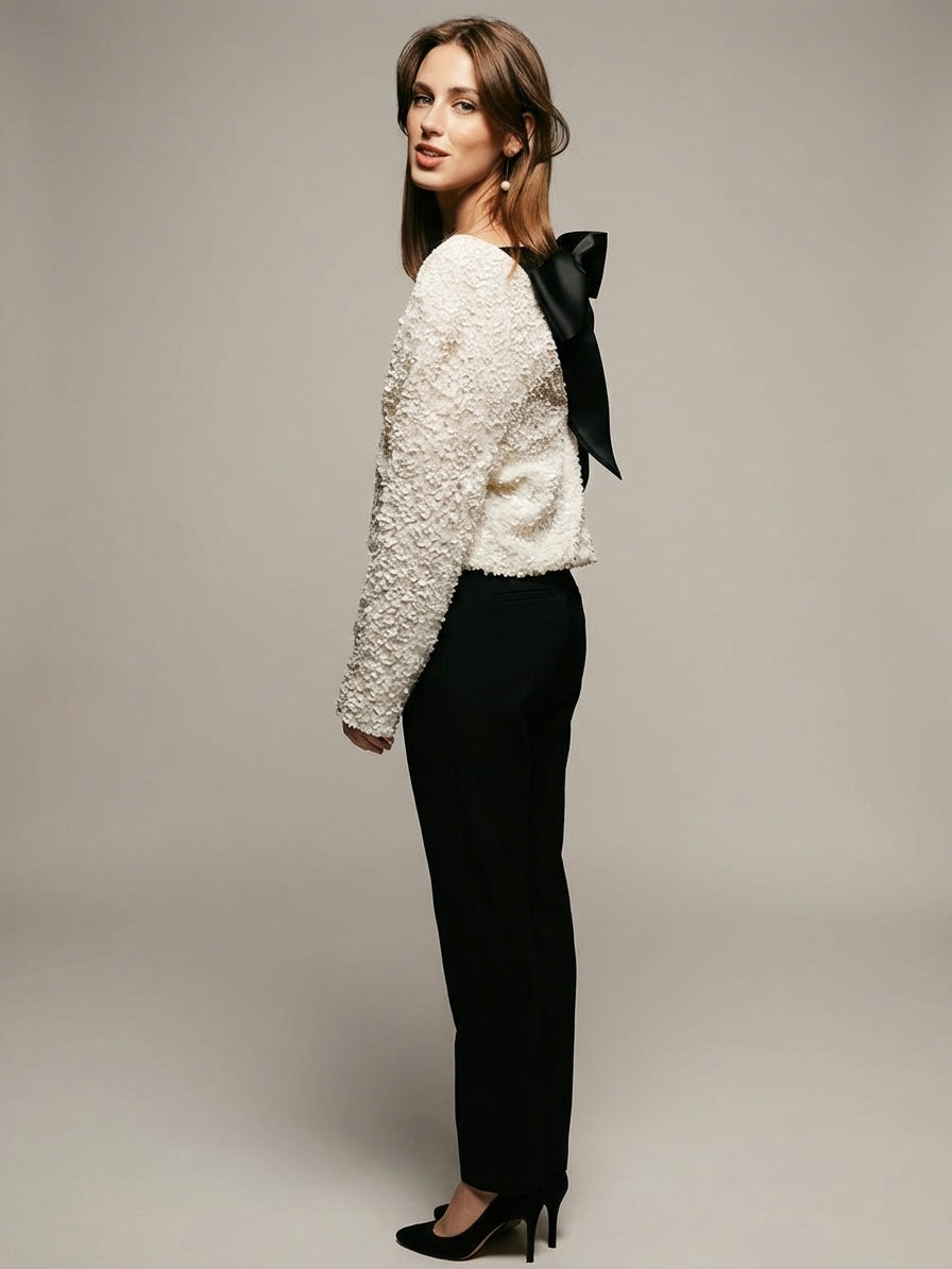 White - Model wearing a cream-coloured, highly textured bouclé knit mini dress with a high neckline, long sleeves, and an A-line silhouette, paired with black pointed-toe heels.