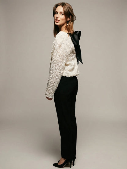 White - Model wearing a cream-coloured, highly textured bouclé knit mini dress with a high neckline, long sleeves, and an A-line silhouette, paired with black pointed-toe heels.