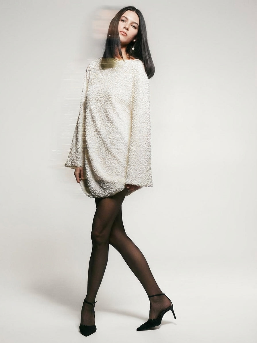 White - Model wearing a cream-coloured, highly textured bouclé knit mini dress with a high neckline, long sleeves, and an A-line silhouette, paired with black pointed-toe heels.