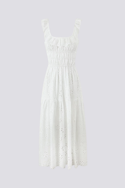 White - A woman wearing a white broderie anglaise maxi dress with a ruffled neckline, smocked waist, and a high thigh slit.
